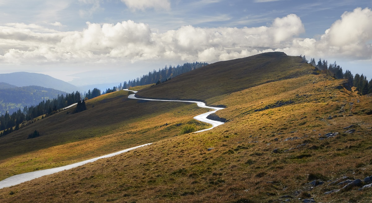 Ein heller Weg führt über eine Bergflanke im Jura